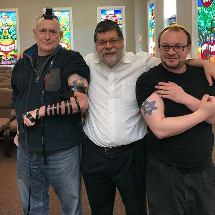 Alon aparece a la derecha indicando su tatuaje representativo junto a su rabino. (Being Libertarian)
