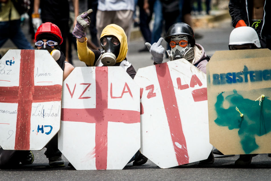 Manifestantes se protegen de la represión con escudos. (Foto: Leo Álvarez)